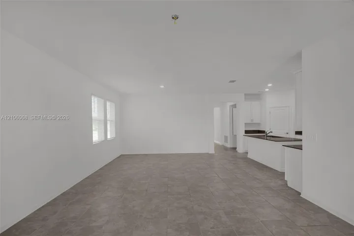 Neutral-toned ceramic tile flooring, recessed lighting, and kitchen island with dark countertops