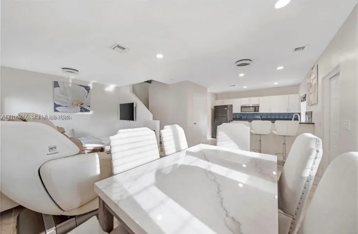 Open-concept interior featuring recessed lighting, a kitchen with flat-panel white cabinetry, and a tiered breakfast bar