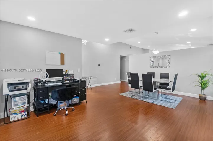 Open-concept floor plan featuring wood-finish flooring, recessed lighting, and a wall-mounted decorative mirror