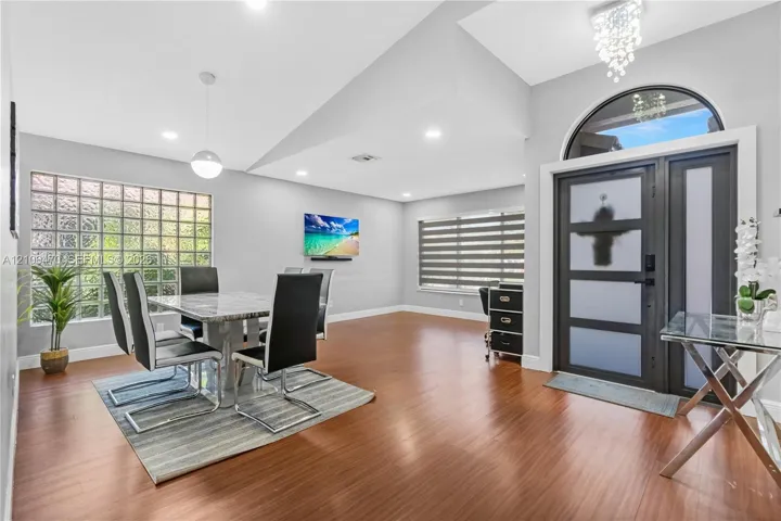 Vaulted ceilings, wood-finish flooring, glass block window, recessed lighting, and an arched-top entry door with frosted glass panels