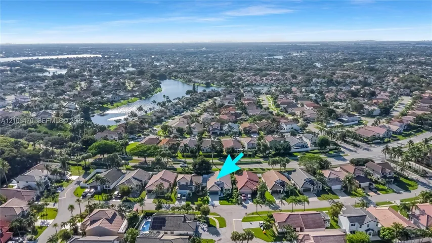 Aerial perspective featuring a single-story residence with a multi-gabled roofline and an integrated garage, situated within a master-planned community