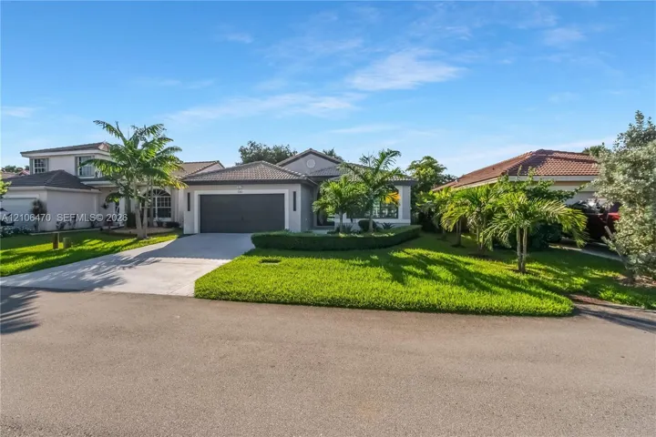 Single-story exterior featuring a concrete tile roof, attached two-car garage, concrete driveway, and manicured landscaping