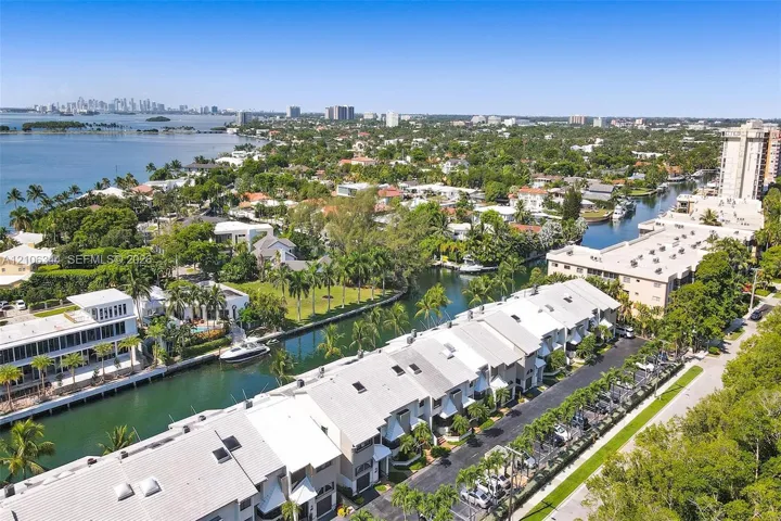 Aerial perspective of waterfront properties featuring deep-water canal access, private boat slips, mature palm trees, and proximity to open bay waters