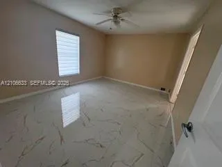Interior room featuring large-format tile flooring with a veined pattern, a ceiling-mounted fan, and a single window with horizontal blinds