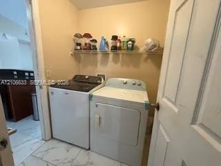 Utility room featuring white stone-finish tile flooring and wall-mounted wire shelving