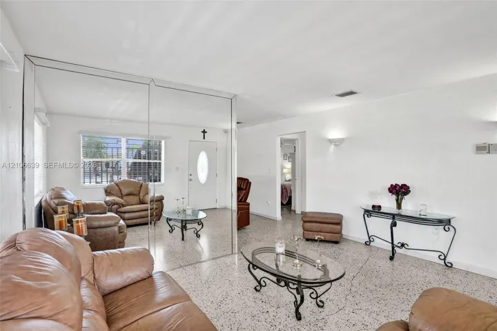 Interior space featuring polished stone-flecked flooring, expansive floor-to-ceiling wall mirrors, and wall-mounted sconce lighting