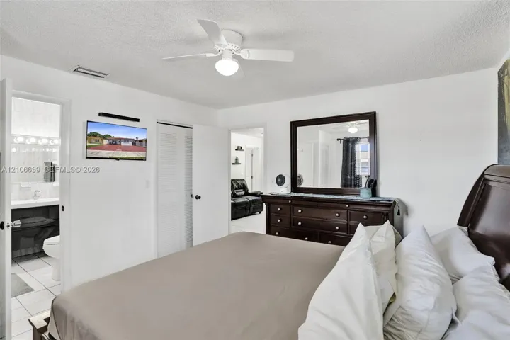 Room featuring a white ceiling fan with integrated light fixture, textured ceiling, and louvered closet doors