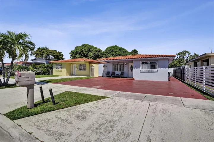 Single-story residence featuring a Mediterranean-style clay tile roof, concrete driveway, and exterior window security bars