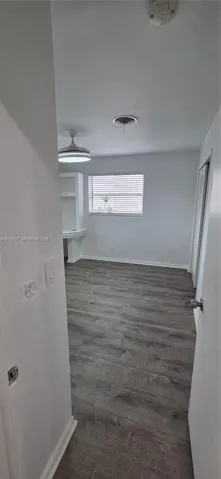 Room featuring wood-finish flooring, a built-in wall niche, a ceiling-mounted light fixture, and horizontal window blinds