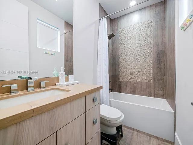 Modern bathroom vanity featuring light wood-finish cabinetry, a rectangular undermount sink, and a countertop with integrated backsplash