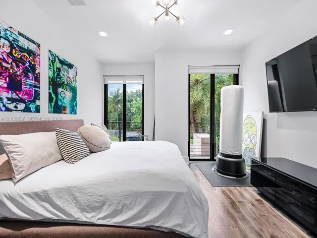 Wood-finish flooring, dual sliding glass doors, recessed lighting, and a multi-arm modern light fixture