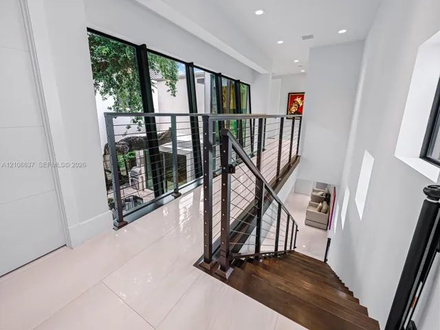 Staircase featuring dark wood treads, floor-to-ceiling windows, stainless steel cable railings, and polished tile flooring