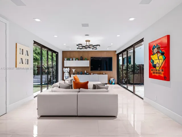 Large-format tile flooring, dual floor-to-ceiling glass sliding door systems, wood-paneled feature wall with built-in cabinetry, and multi-light geometric chandelier