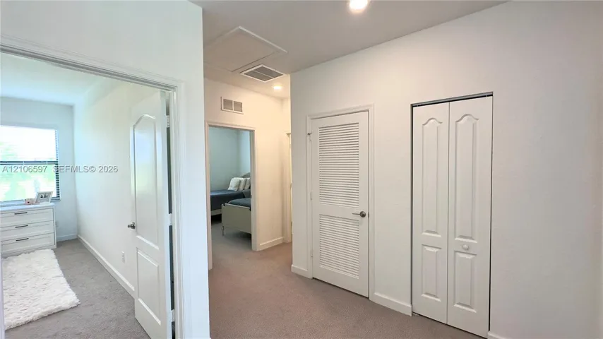 Neutral-toned carpeting, white arched-panel interior doors, and white louvered closet doors
