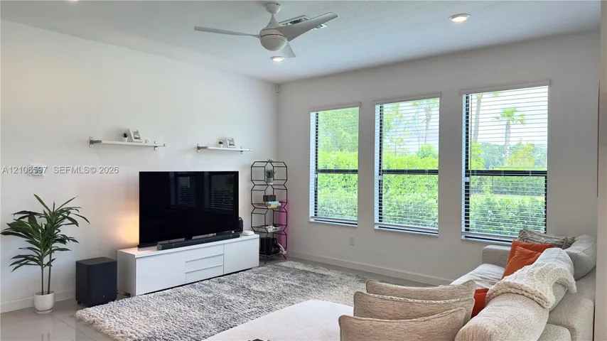 Interior space featuring a three-panel window configuration, recessed ceiling lighting, a dual-blade ceiling fan, and two wall-mounted display shelves