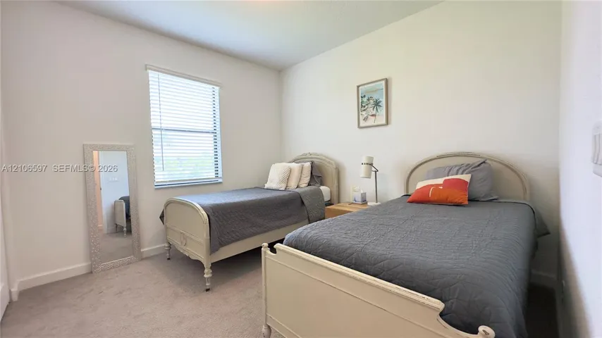 Neutral-toned wall-to-wall carpeting and a single-hung window featuring horizontal blinds