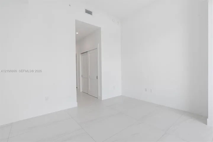 Interior space featuring large-format rectified tile flooring, recessed ceiling lighting, and double-panel sliding closet doors