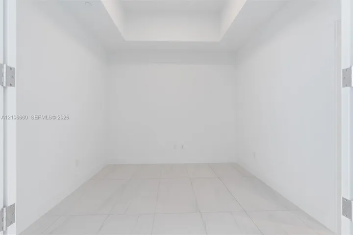 Interior space featuring a recessed ceiling, white walls, and large-format tile flooring