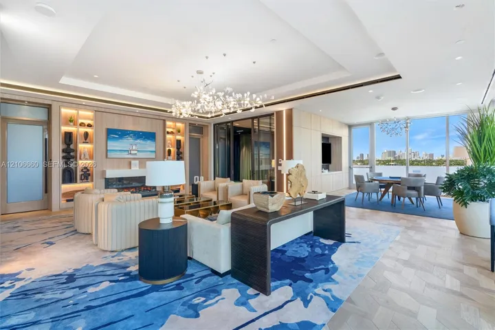 Expansive living area featuring a tray ceiling, integrated custom shelving with built-in accent lighting, a linear fireplace, wood-finish herringbone flooring, and floor-to-ceiling windows