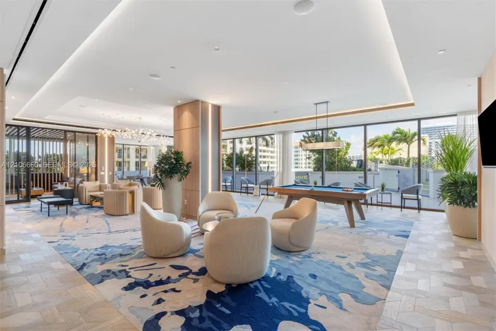 Expansive open-concept space featuring herringbone-patterned wood-finish flooring, floor-to-ceiling glass paneling, recessed cove lighting, and floor-to-ceiling wooden column detailing
