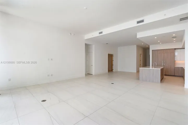 Open-concept interior featuring large-format tile flooring, recessed ceiling lighting, and a kitchen island with stone countertops