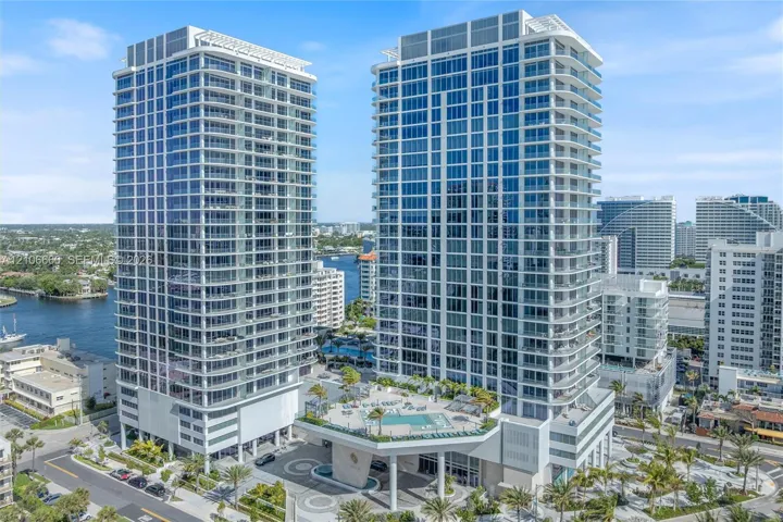 High-rise residential towers featuring floor-to-ceiling glass paneling, wrap-around balconies, an elevated podium pool deck, and structured covered entryway