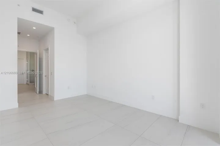 High-ceiling interior featuring smooth white walls, large-format tile flooring with marble-style veining, recessed lighting, and solid-core interior doors