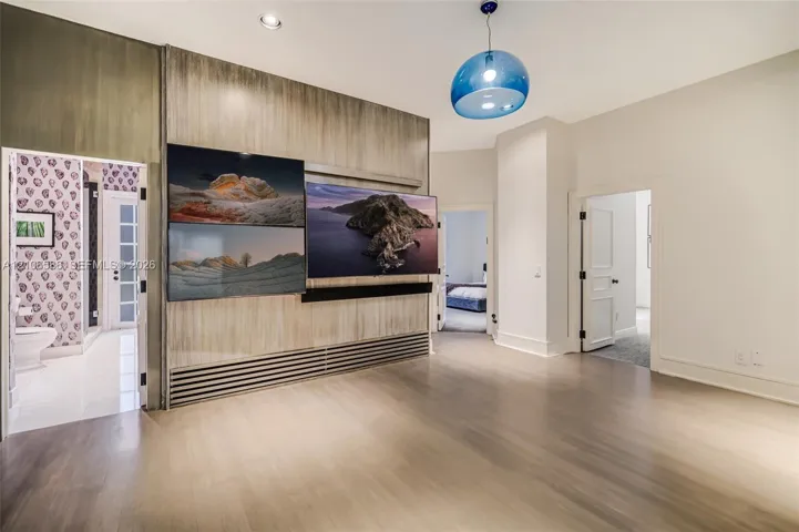 Wood-finish wall paneling with integrated media station, recessed ceiling lighting, and blue glass pendant fixture