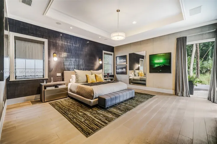 Tray ceiling with recessed lighting, wood-finish flooring, textured wall covering, wall-mounted accent lighting, and glass door entry to exterior space