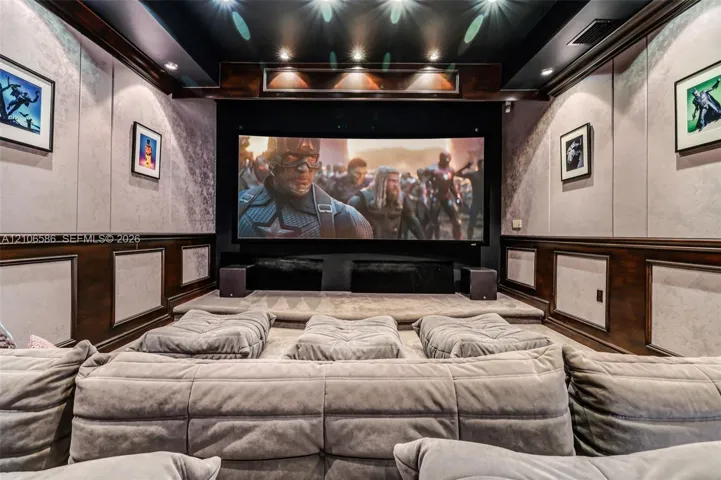 Dedicated screening room featuring a tiered floor, custom wood wainscoting, recessed ceiling lighting, and integrated wall paneling