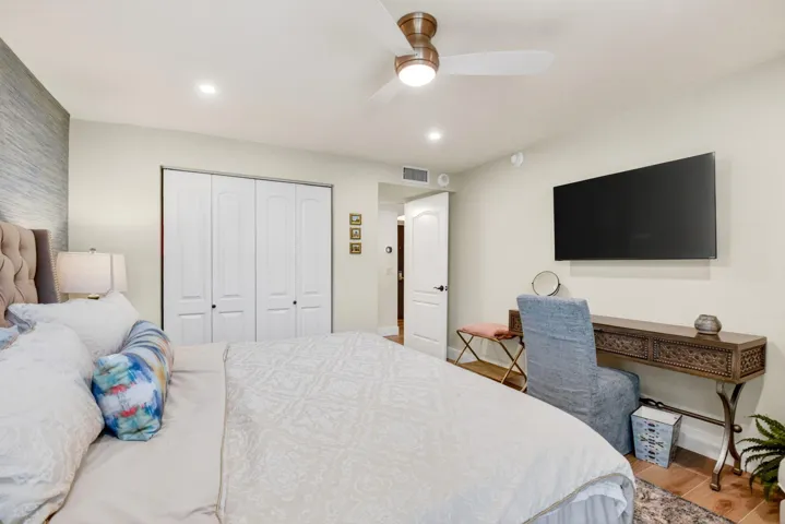 Textured accent wall, ceiling fan with integrated lighting, four-panel closet doors, and recessed overhead lighting
