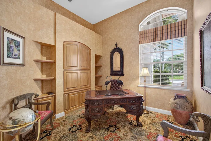 Room featuring custom built-in wood cabinetry with integrated shelving and an arched window with a fanlight