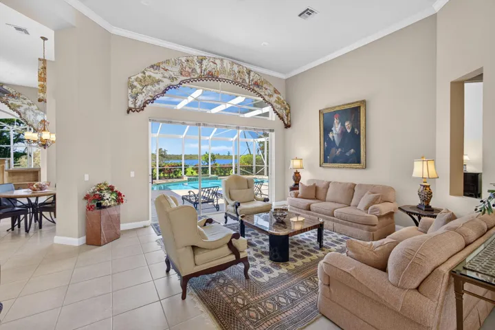 Living area featuring high ceilings, large arched decorative detailing above sliding glass doors, neutral tile flooring, and recessed lighting