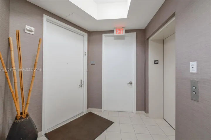 Textured wall covering in a neutral finish, light-colored tile flooring, and integrated elevator access