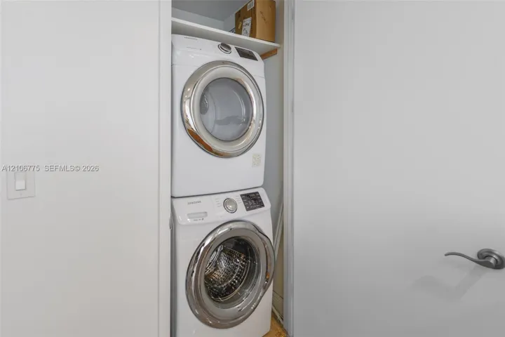 Stacked front-loading washer and dryer unit with built-in overhead shelving housed within a dedicated closet