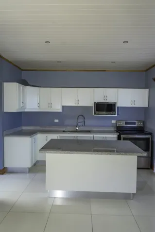 Kitchen featuring white cabinetry, an island with stone-finish countertop, stainless steel appliances, recessed ceiling lighting, and tile flooring
