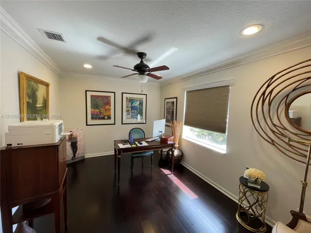 Room featuring dark wood-finish flooring, crown molding, a central ceiling fan with integrated lighting, and recessed overhead lighting