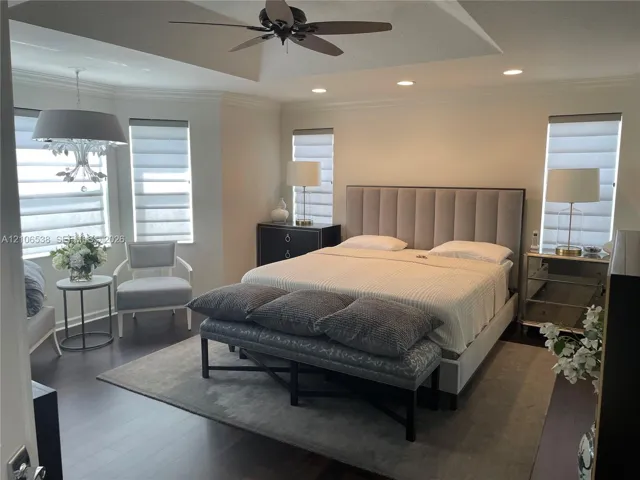 Tray ceiling with integrated recessed lighting, dark wood-finish flooring, bay window configuration, and an overhead ceiling fan