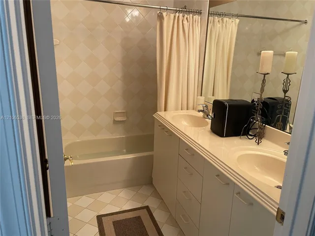 Full vanity with dual integrated sinks, diamond-patterned wall tiling, and a recessed bathtub with a shower surround