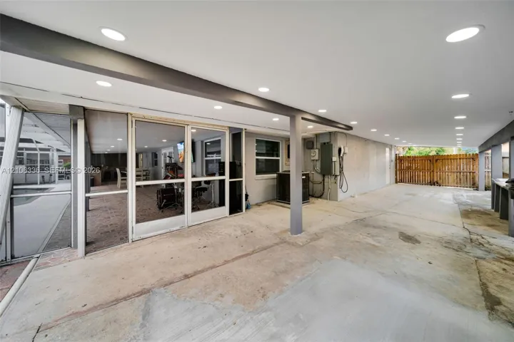 Covered concrete patio featuring recessed ceiling lighting, a screened enclosure, and a wood-slat privacy fence