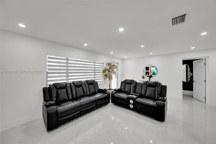 Large-format tile flooring, recessed ceiling lighting, and horizontal louvered window blinds