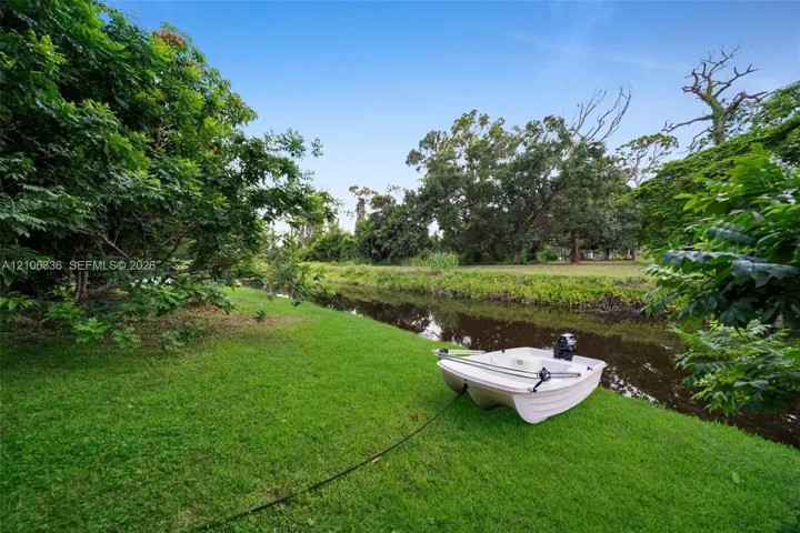 Waterfront lot featuring a manicured lawn, established trees, and natural vegetation