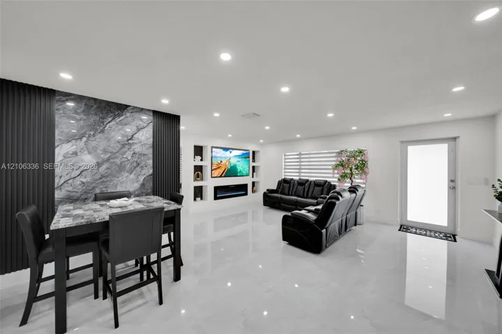 Open-concept interior featuring large-format polished tile flooring, recessed lighting, and a floor-to-ceiling stone accent wall with vertical slat detailing