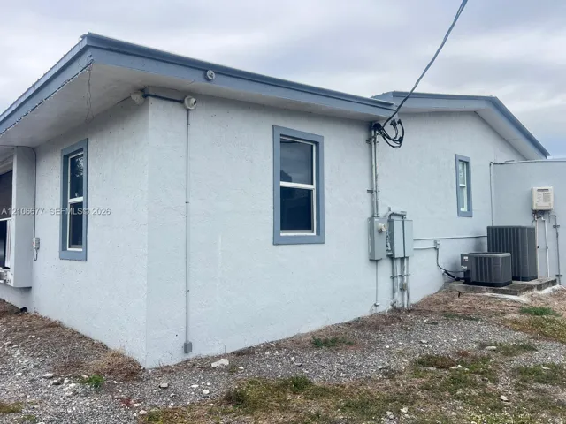 Stucco exterior featuring multi-paned windows, neutral trim, and dual exterior HVAC condenser units