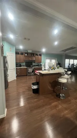 Kitchen featuring wood cabinetry, a center island with a stone-finish countertop, recessed lighting, and wood-finish flooring