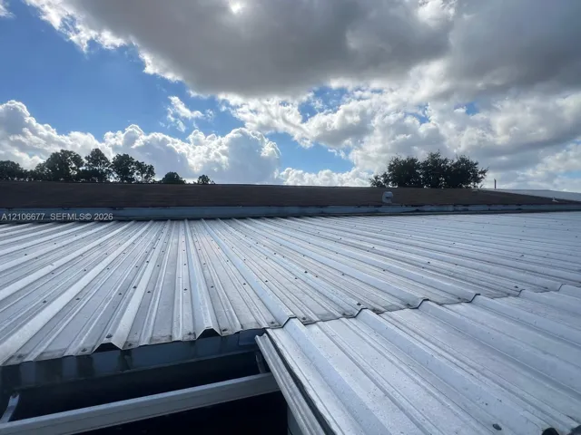 Corrugated metal roofing system paired with shingle roof sections