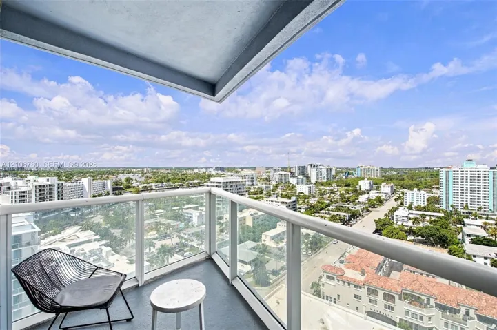 Private balcony featuring a glass panel railing and elevated exterior perspective of the surrounding area