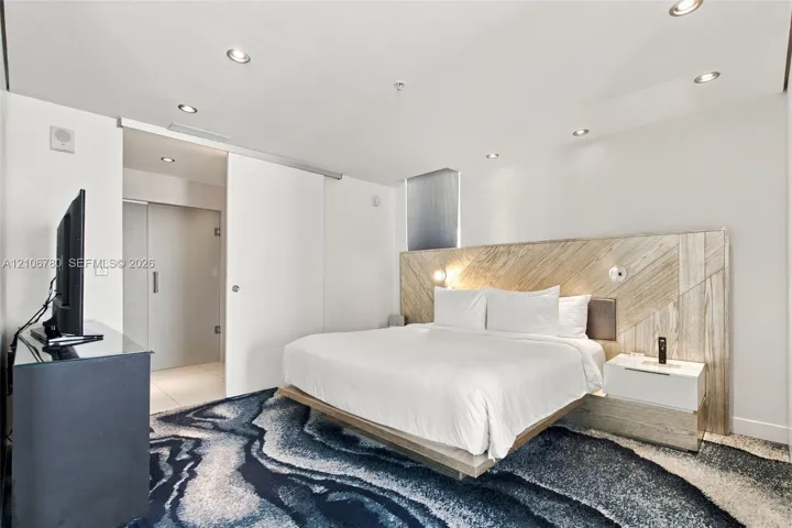 Recessed ceiling lighting, wood-paneled feature wall, floating platform base, and sliding interior door