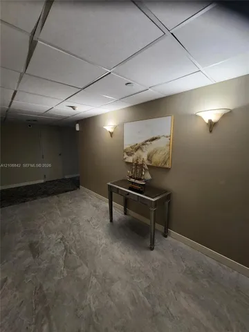 Large-format stone-tile flooring and recessed drop-ceiling grid with integrated wall-mounted sconce lighting