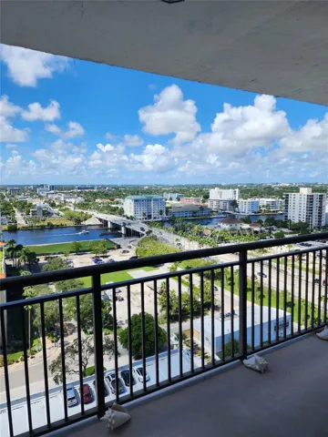 Covered balcony featuring black metal railings and panoramic water and city scenery